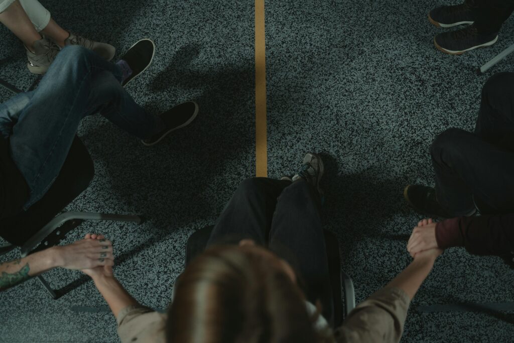 A diverse group of people holding hands in a circle, symbolizing support and unity in a mental health session.