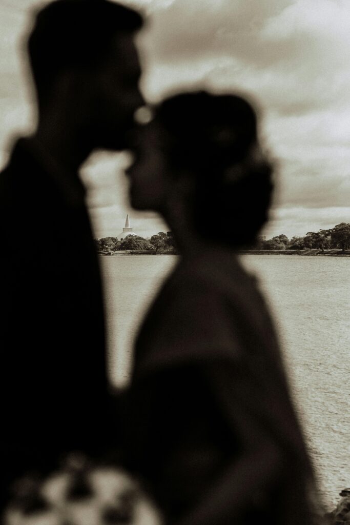 Romantic silhouette of a couple kissing by the water at sunset. Perfect for love-themed content.