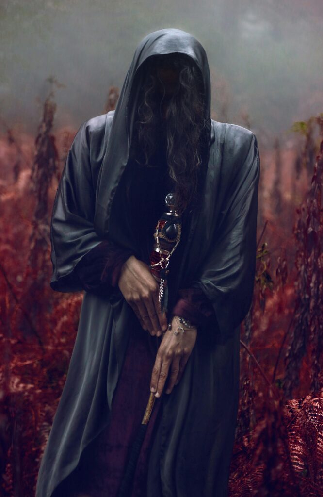 Faceless figure in hooded robe amidst mystical red forest at dawn, evoking mystery.