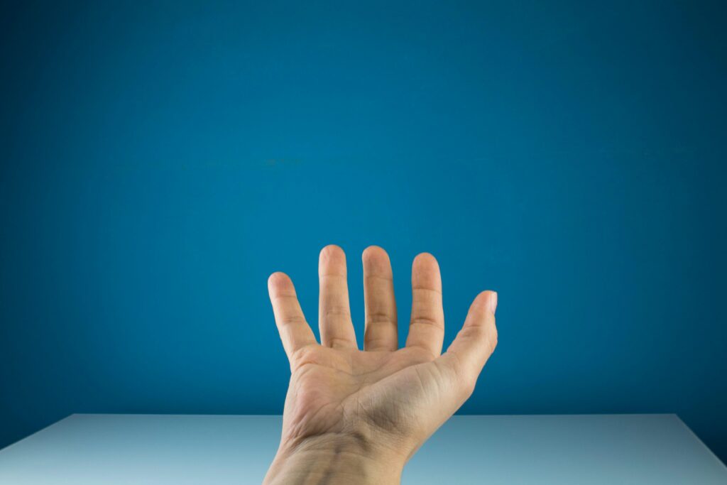 Open hand reaching against a solid blue background, suitable for conceptual themes or presentations.