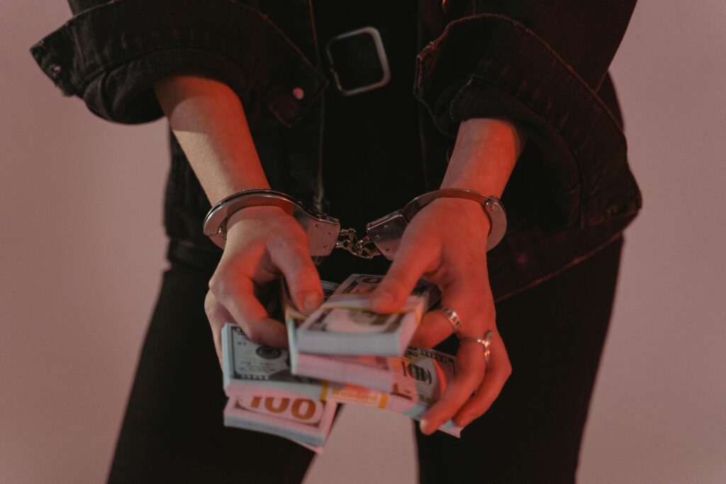 Close-up of hands holding cash with handcuffs, symbolizing crime and punishment.